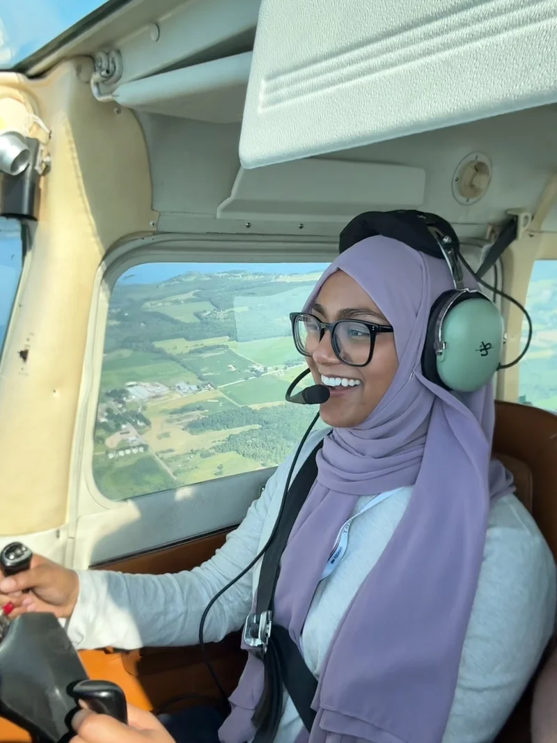 Zarin wearing a headset at the controls of an aircraft in flight