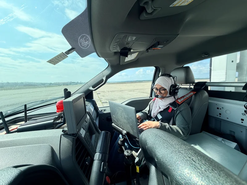 Zarin wearing a headset and safety harness while working on a laptop inside a test truck